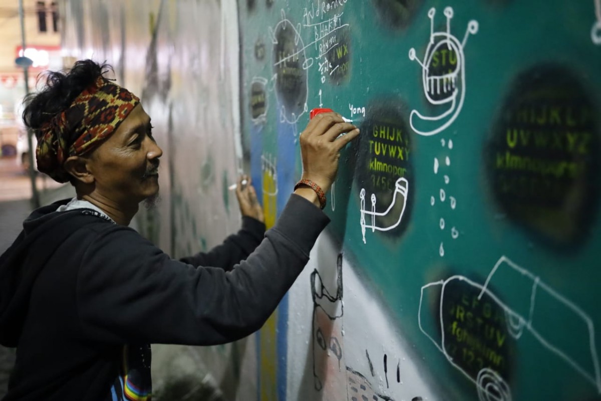 Edi saat sedang membuat mural di dinding kawasan Pecinan Pasar Lama, Tangerang